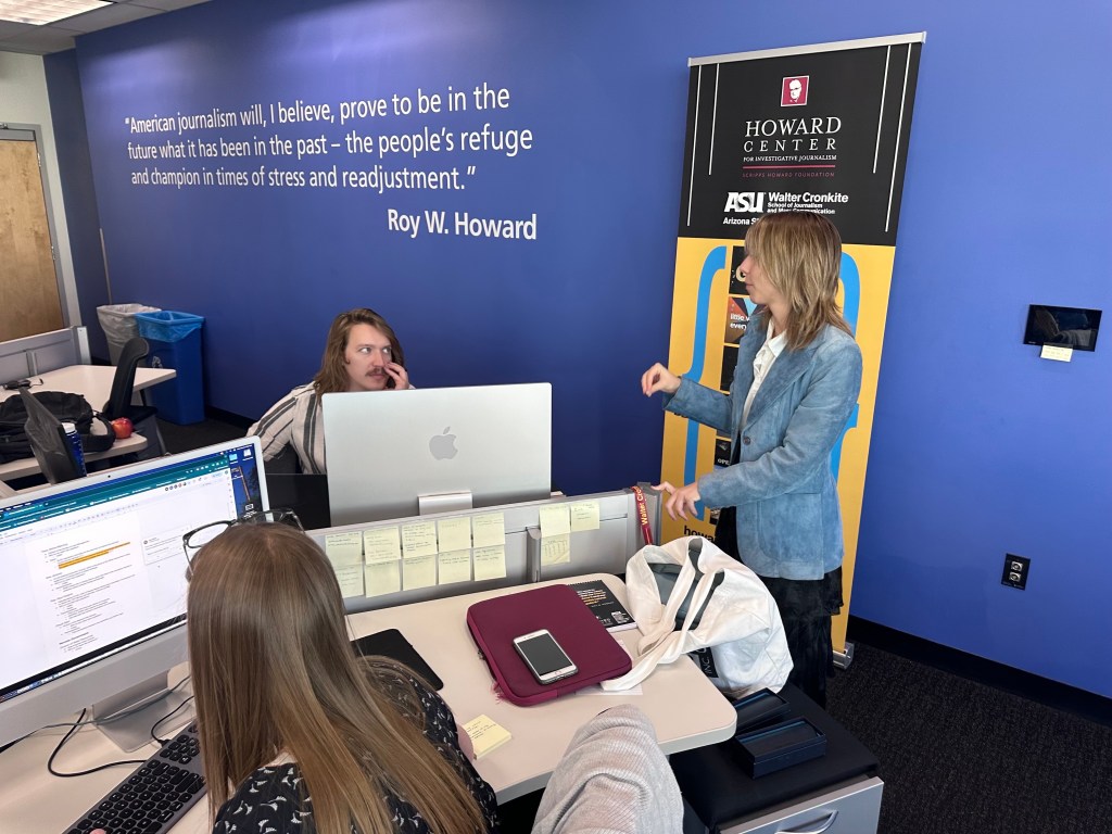 Tori Gantz is enveloped in dialogue with co-reporters in the Howard Center for Investigative Journalism at Arizona State University's Walter Cronkite School of Journalism and Mass Communication.